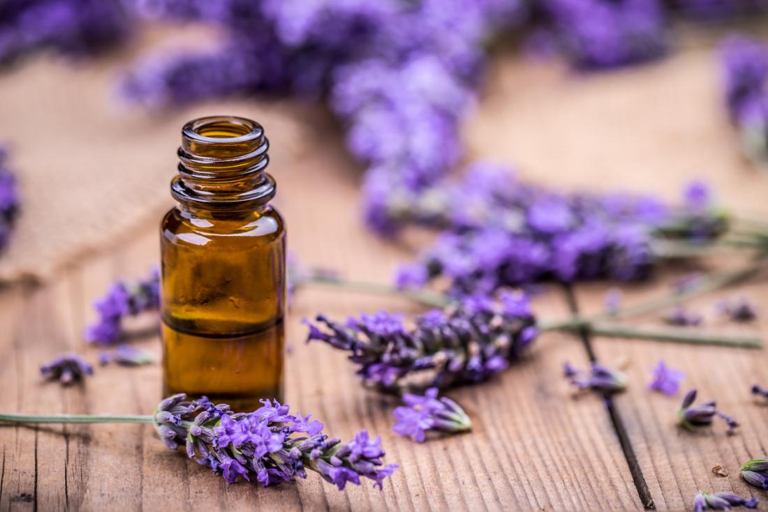 A small brown bottle on a table surrounded by sprigs of lavender blooms
